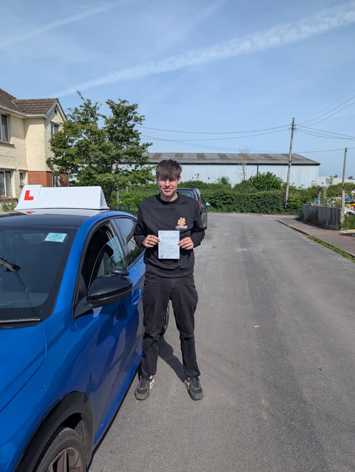 A successful learner stands beside the tuition car